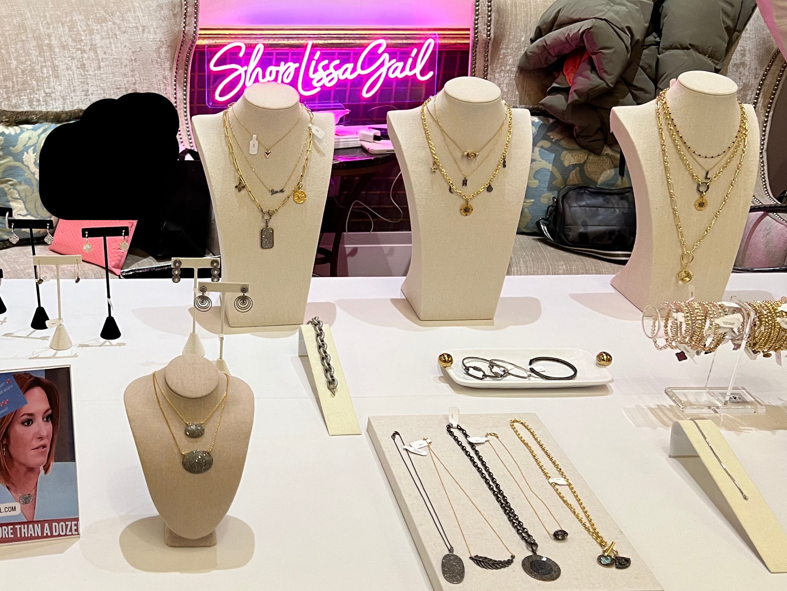Table set up with multiple pieces of jewelry and Shop Lissa Gail sign in background 