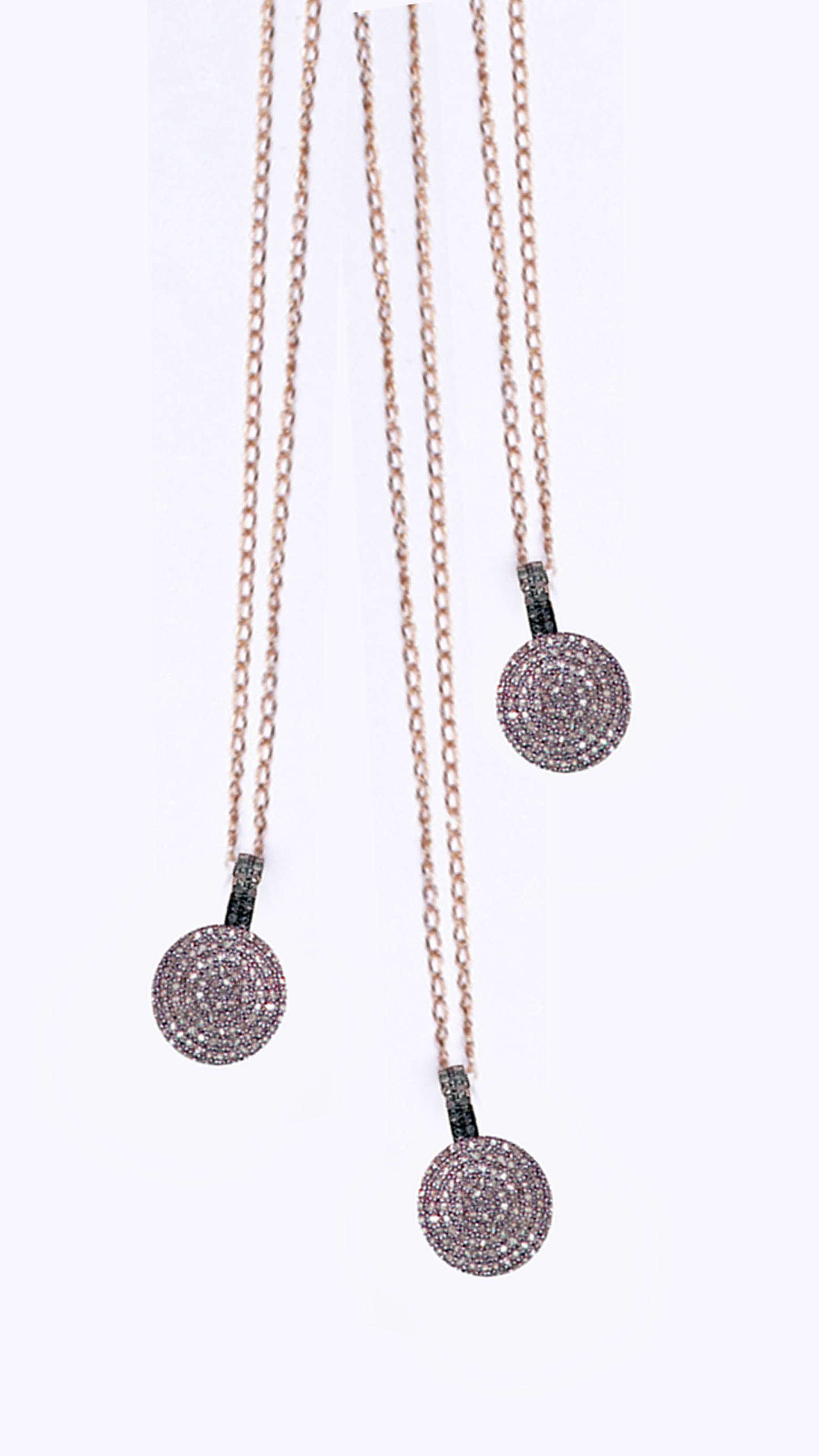 Three necklaces with circular pendants on a white background